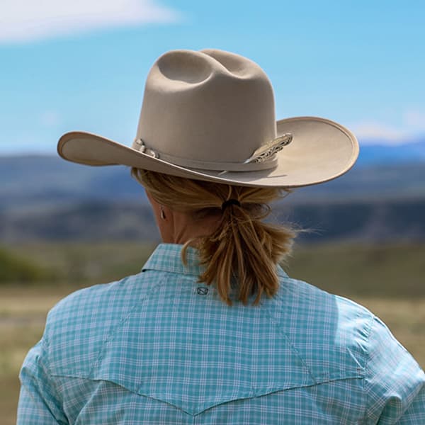 Women wearing cowboy hat with feather hat pick