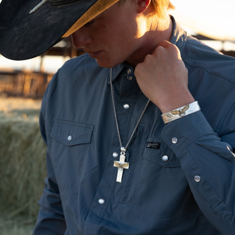 Man wearing cross necklace and eagle figure bracelet.